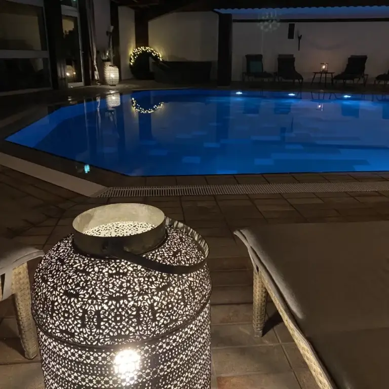 Pool mit Liegestühlen und gemütlichem Licht am Abend